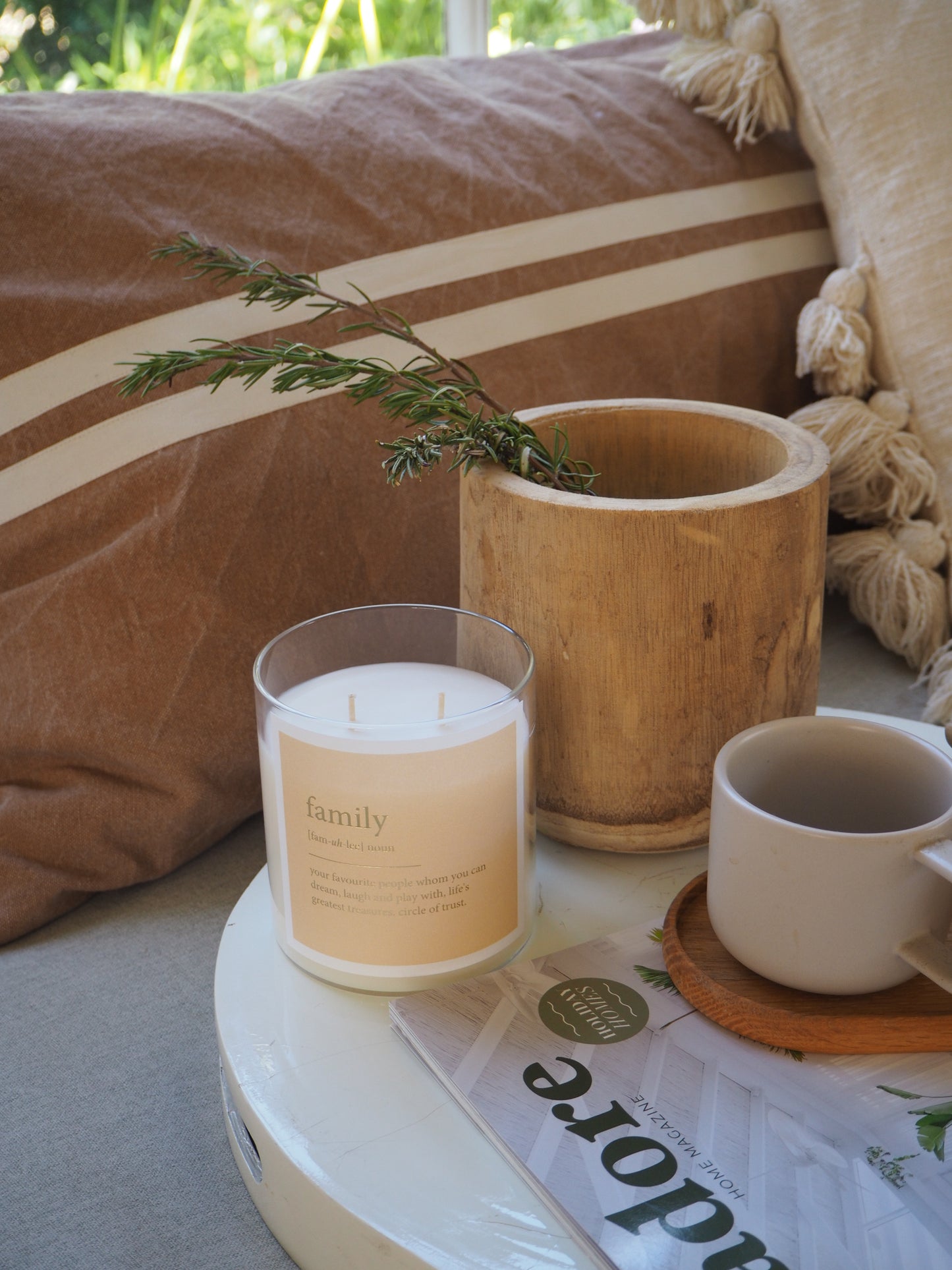 A magazine rests on a table beside a cup of coffee and a scented soul candle