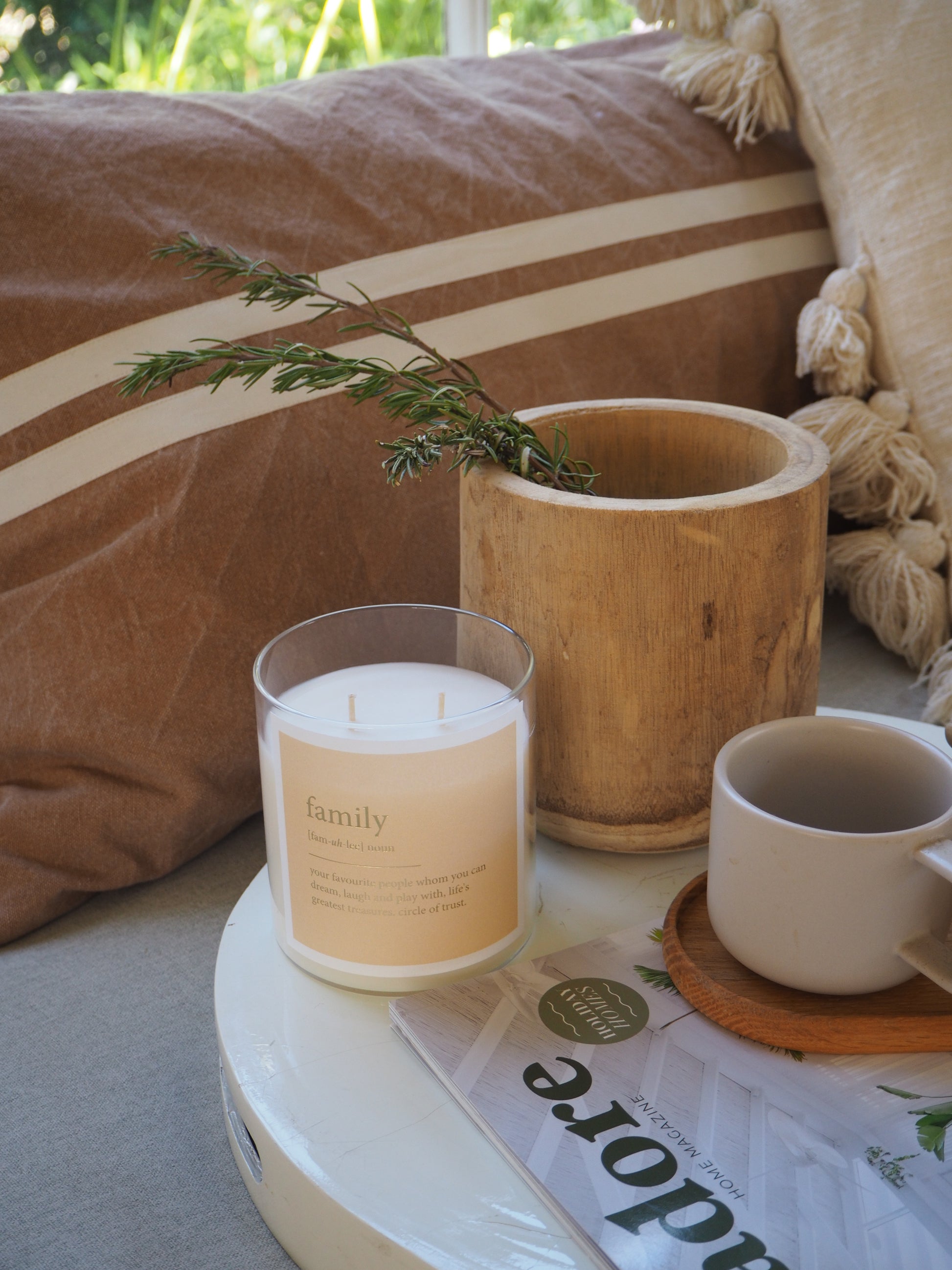 A magazine rests on a table beside a cup of coffee and a scented soul candle
