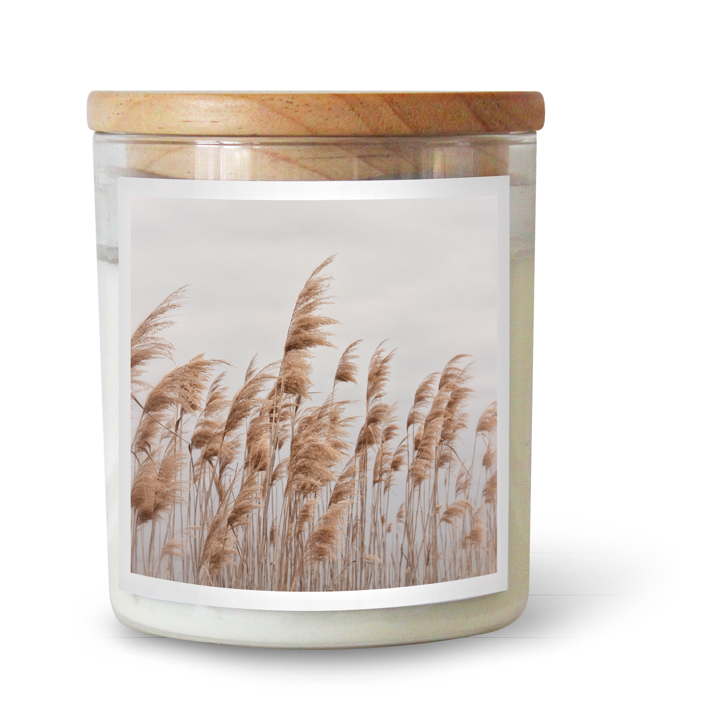 The Commonfolk scented candle comes in a clear glass jar with a wooden lid, featuring an image of pampas grass on the label.