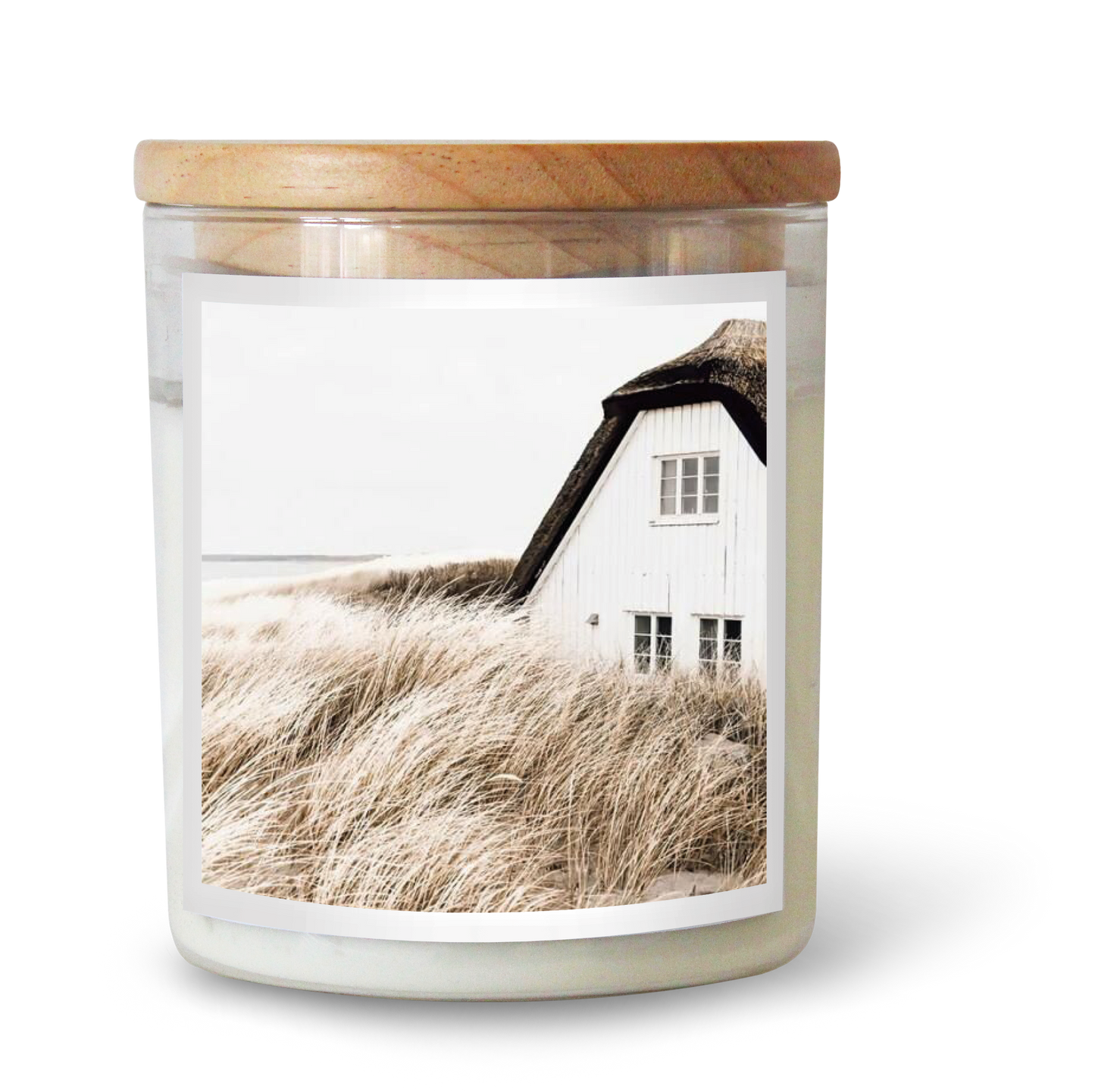 The Commonfolk scented candle has a label featuring a white house by the sea, with tall grass in the foreground.