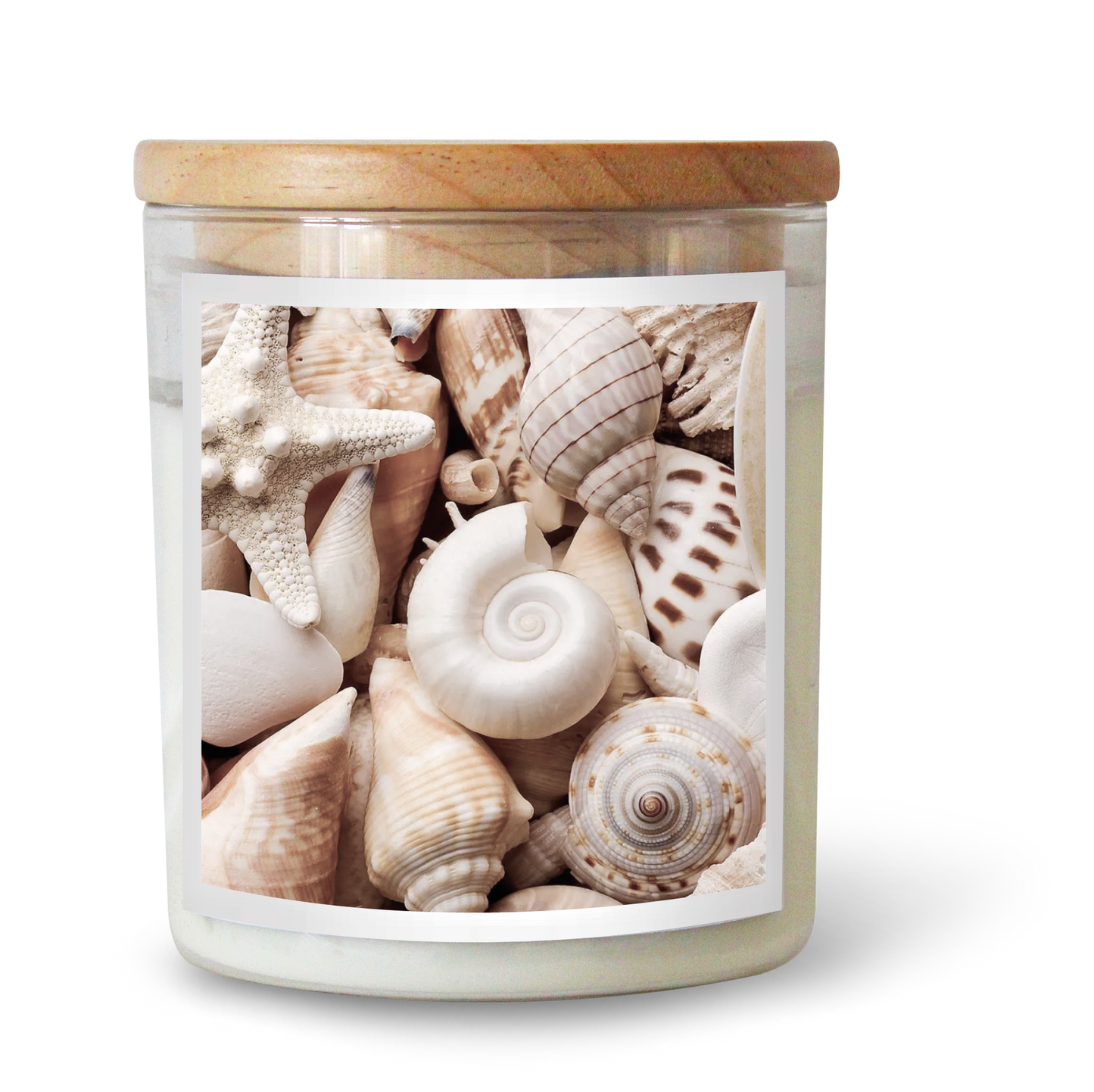 The Commonfolk scented candle comes in a clear jar containing various seashells and has a wooden lid.
