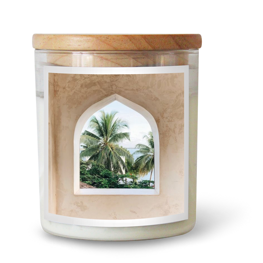 The Commonfolk scented candle features white wax and a window-like design on the label showcasing a tropical scene with palm trees.
