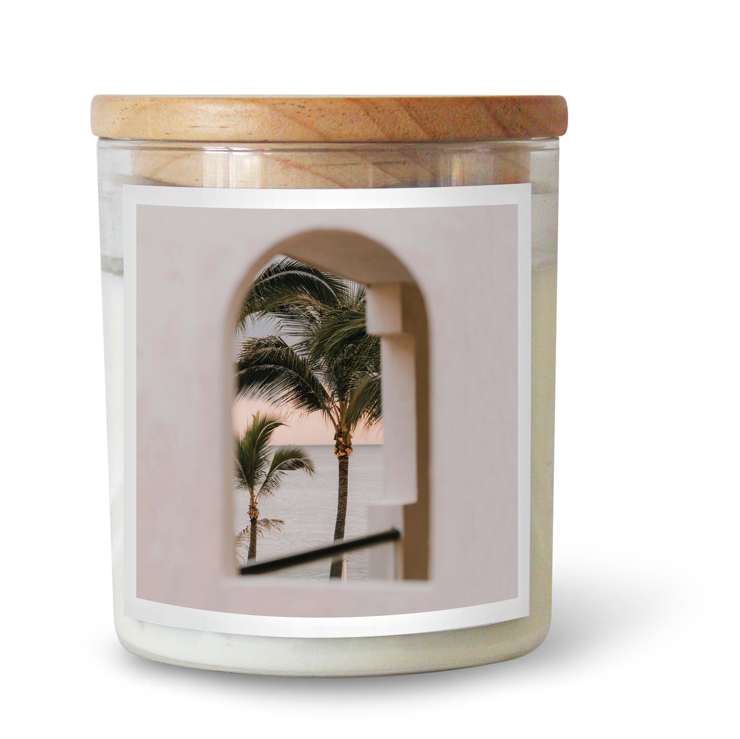 The Commonfolk scented candle, with a white label featuring an image of palm trees, is topped with a wooden lid.