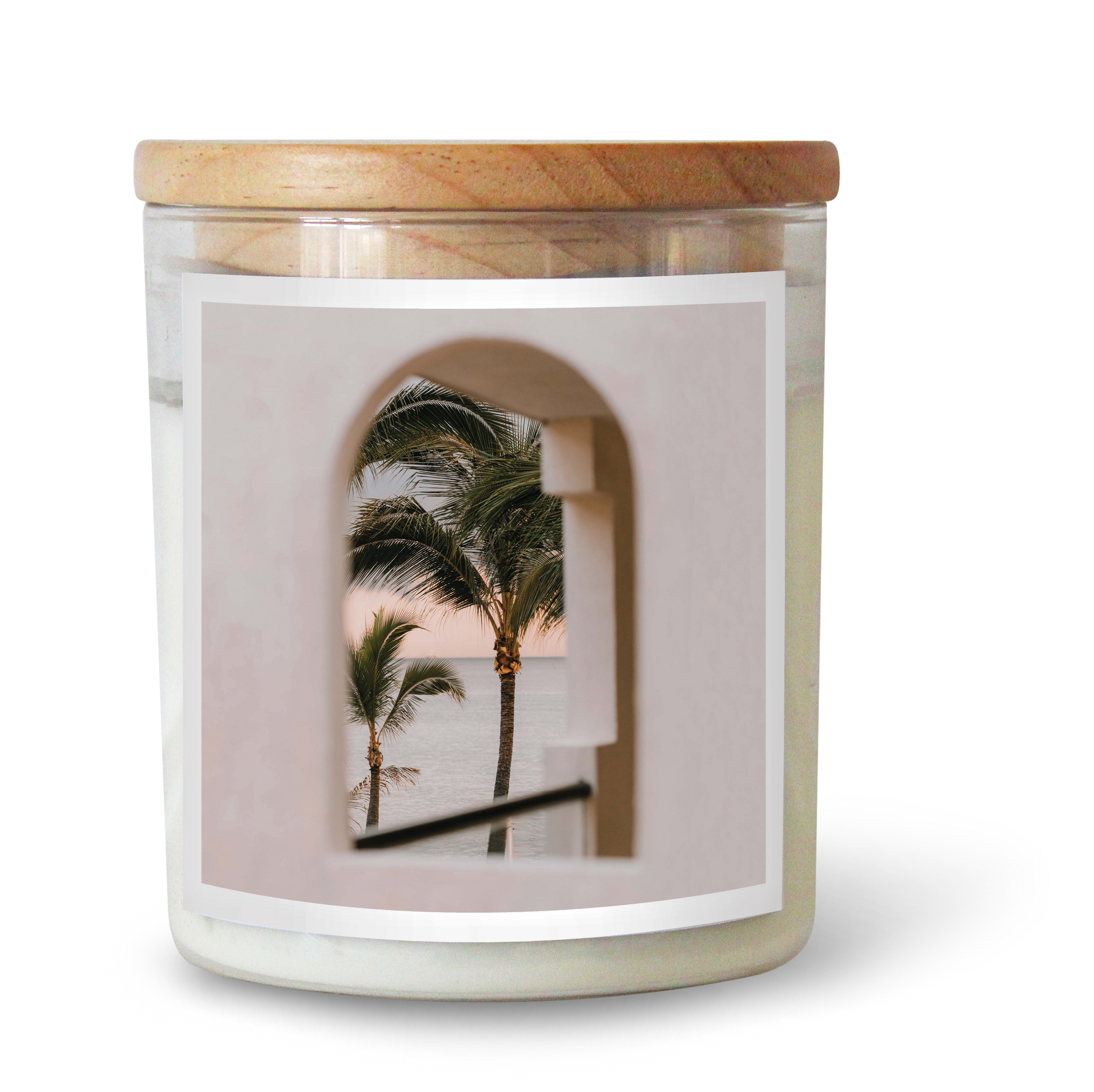The Commonfolk scented candle, with a white label featuring an image of palm trees, is topped with a wooden lid.