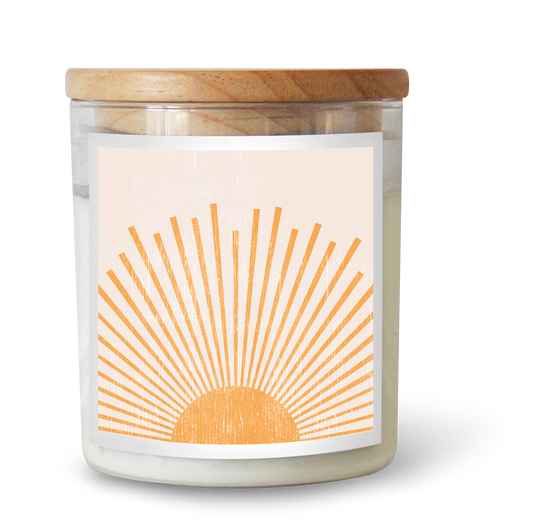 The Commonfolk scented white candle with a sun dial design in orange, set in a clear glass jar with a wooden lid.