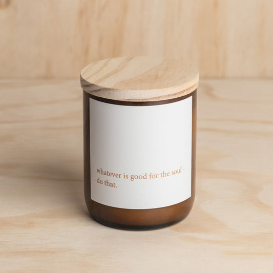 The Commonfolk scented candle with a white label on it, wooden lid, and the text 'whatever is good for the soul, do that.'