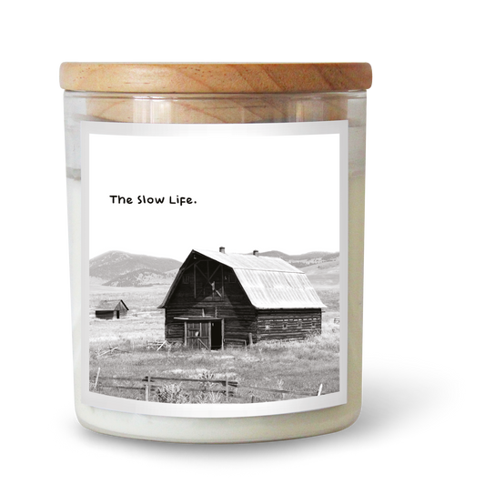 The Commonfolk scented candle features a label with a black and white photo of a barn and the text 'The Slow Life' on it.