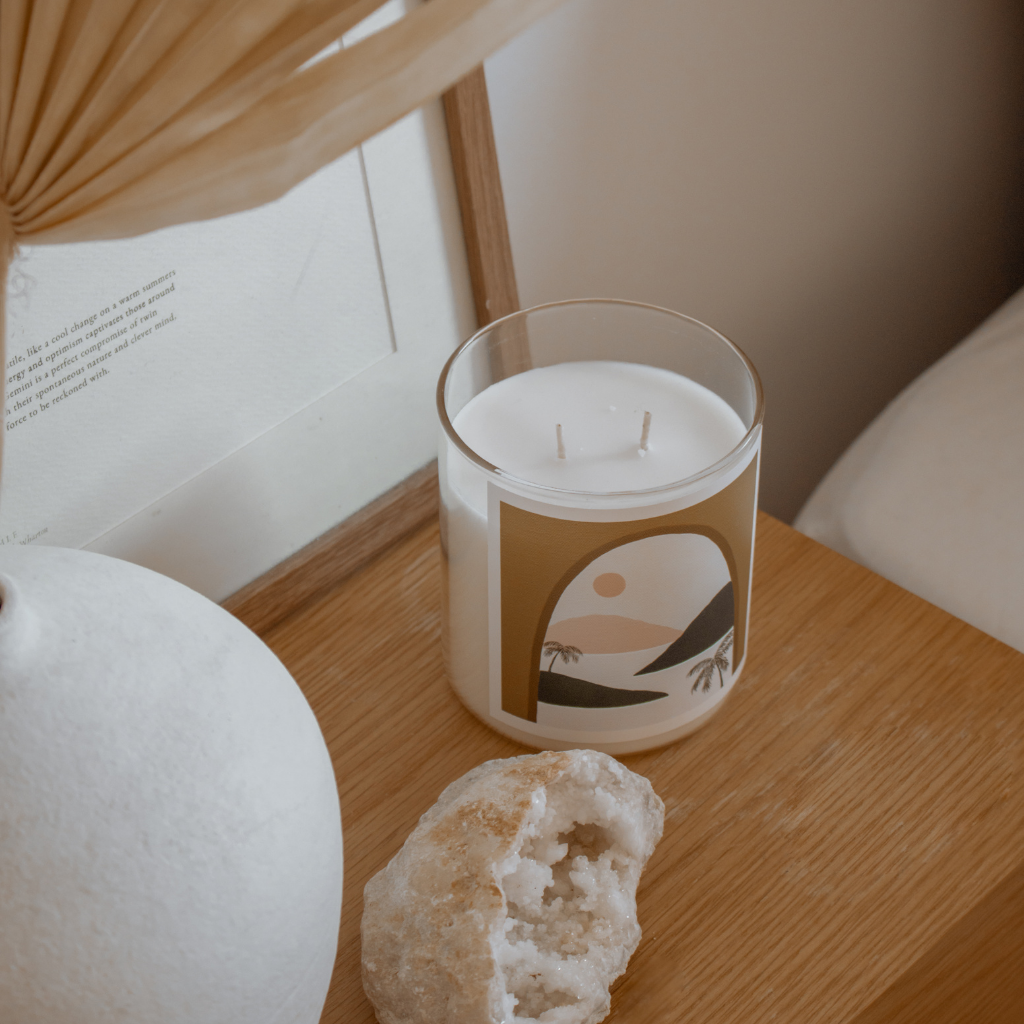 A candle and a rock sit on a table beside a framed picture, creating a serene and decorative arrangement.