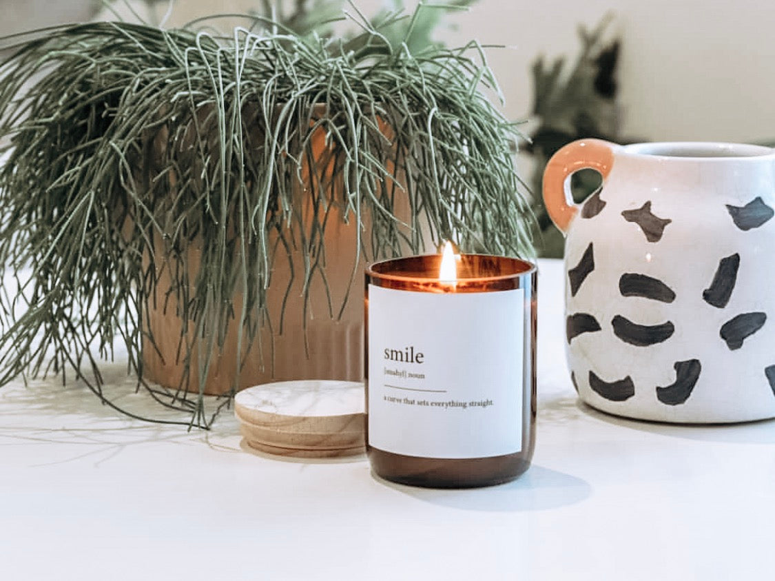 A candle beside a potted plant on a wooden table, creating a cozy and inviting atmosphere.