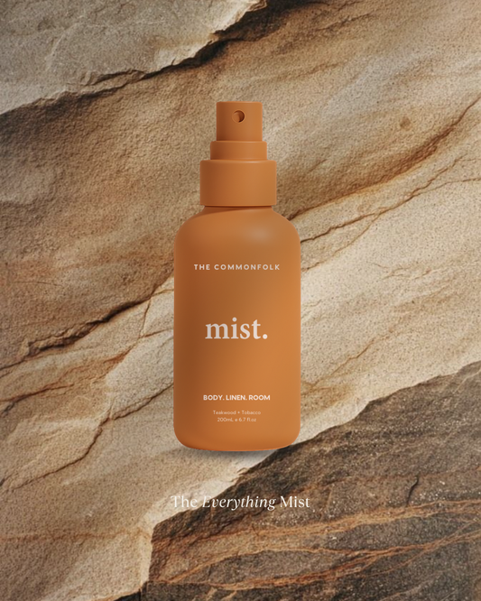 Orange spray bottle labeled 'mist.' by 'The Commonfolk' on a stone background