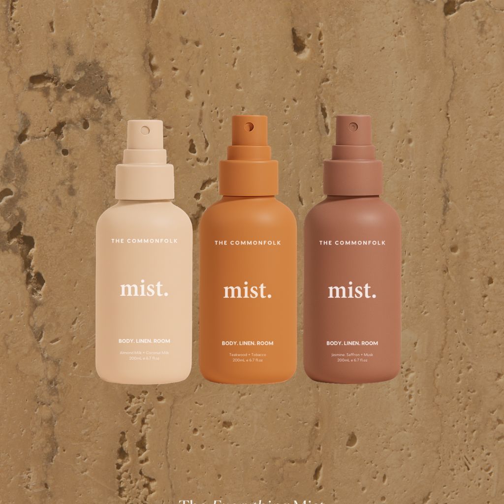 Three 'The Commonfolk' mist bottles in beige, orange, and brown on a textured beige background.