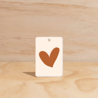 The Commonfolk air freshener, with a heart shape cut out in the center on a white background.