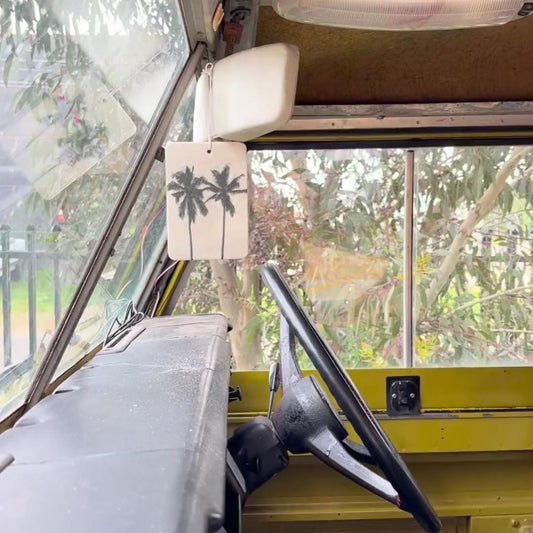 Steering wheel inside a vehicle with a palm tree decal on the windshield