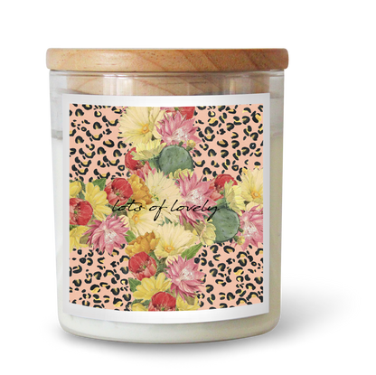 The Commonfolk scented candle has a floral pattern on its label, featuring a mix of flowers and the text 'Lots of Lovely.' The label is predominantly pink with a leopard print design around the edges.