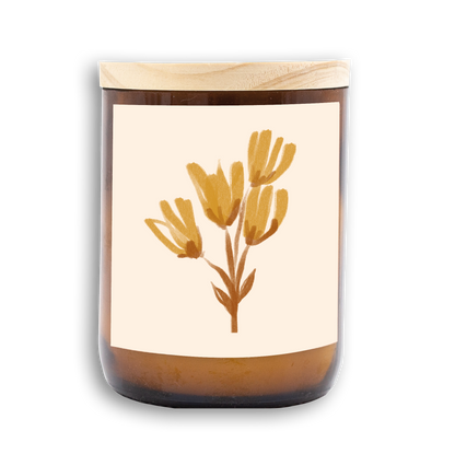 The Commonfolk scented mid-sized candle has a floral design on the label, predominantly yellow and white, with a wooden lid.