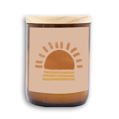 The Commonfolk scented mid-sized candle features a beige label with a brown sun illustration on an amber glass jar with a wooden lid.