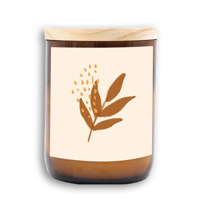 The Commonfolk scented mid-sized candle has a leaf design on its label, predominantly in a beige color, with a wooden lid.