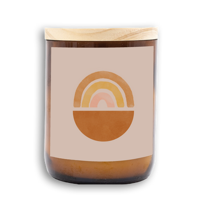 The Commonfolk scented mid-sized candle features a rainbow root design on the label, an amber-colored jar, and a wooden lid.