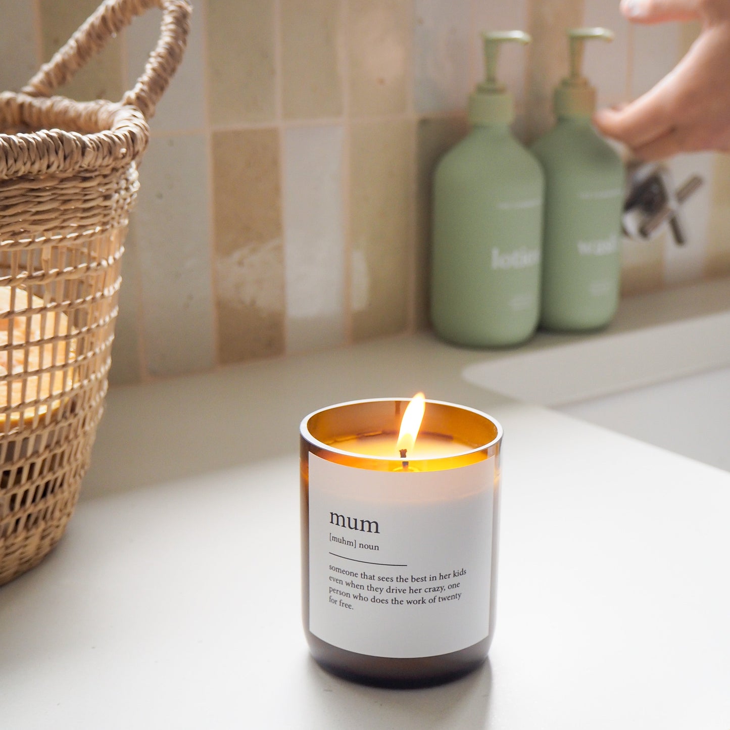 Candle labeled 'mum' on a kitchen counter with a hand reaching towards it.