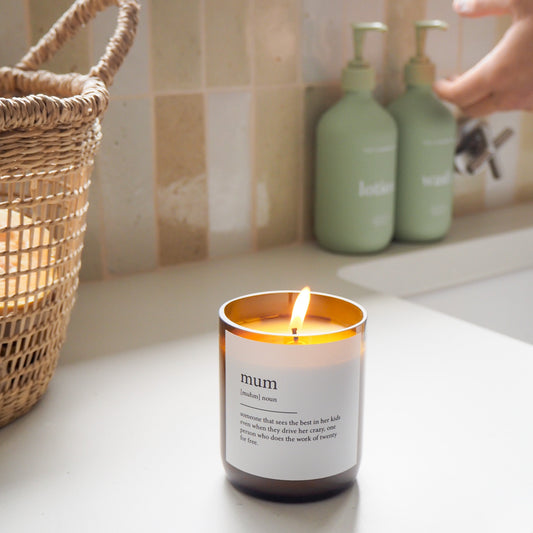 Candle labeled 'mum' on a kitchen counter with a hand reaching towards it.