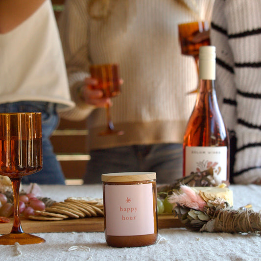 People enjoying a festive gathering with a bottle of wine and a candle on a table.
