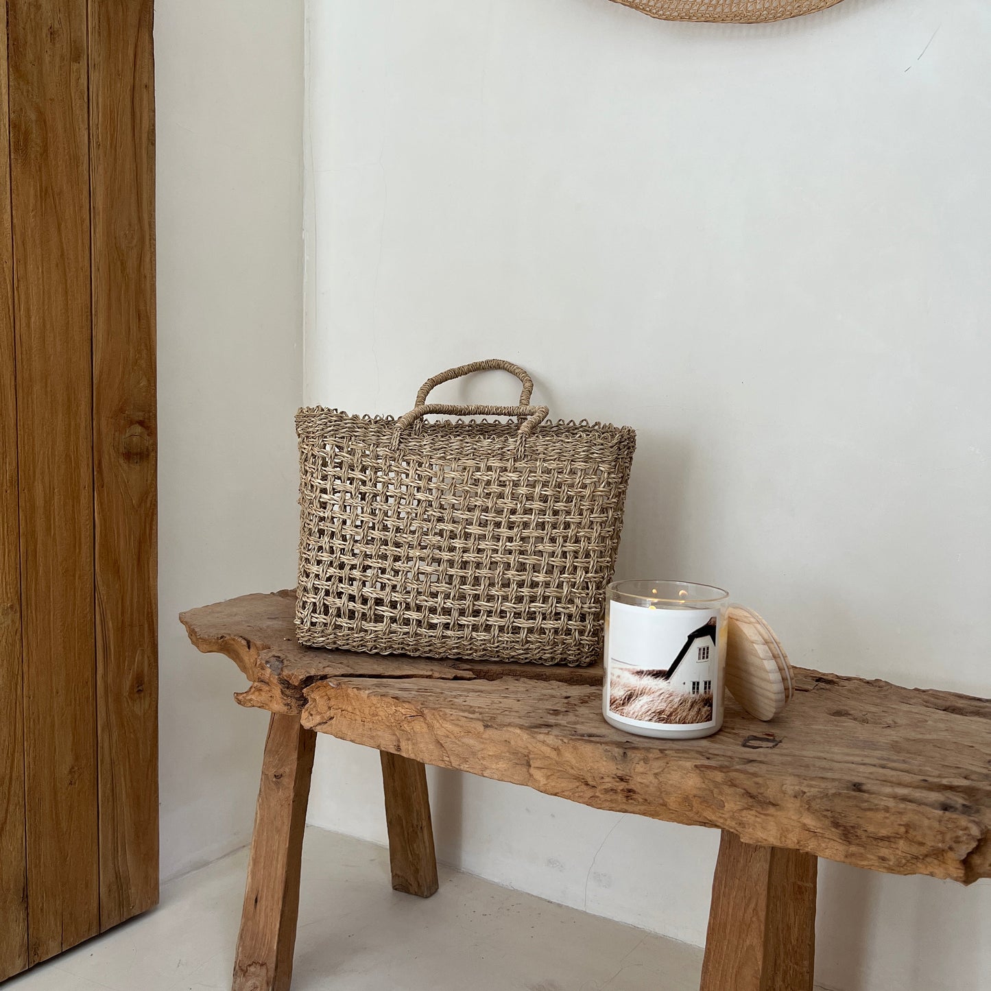 Woven basket on a wooden stool against a white wall