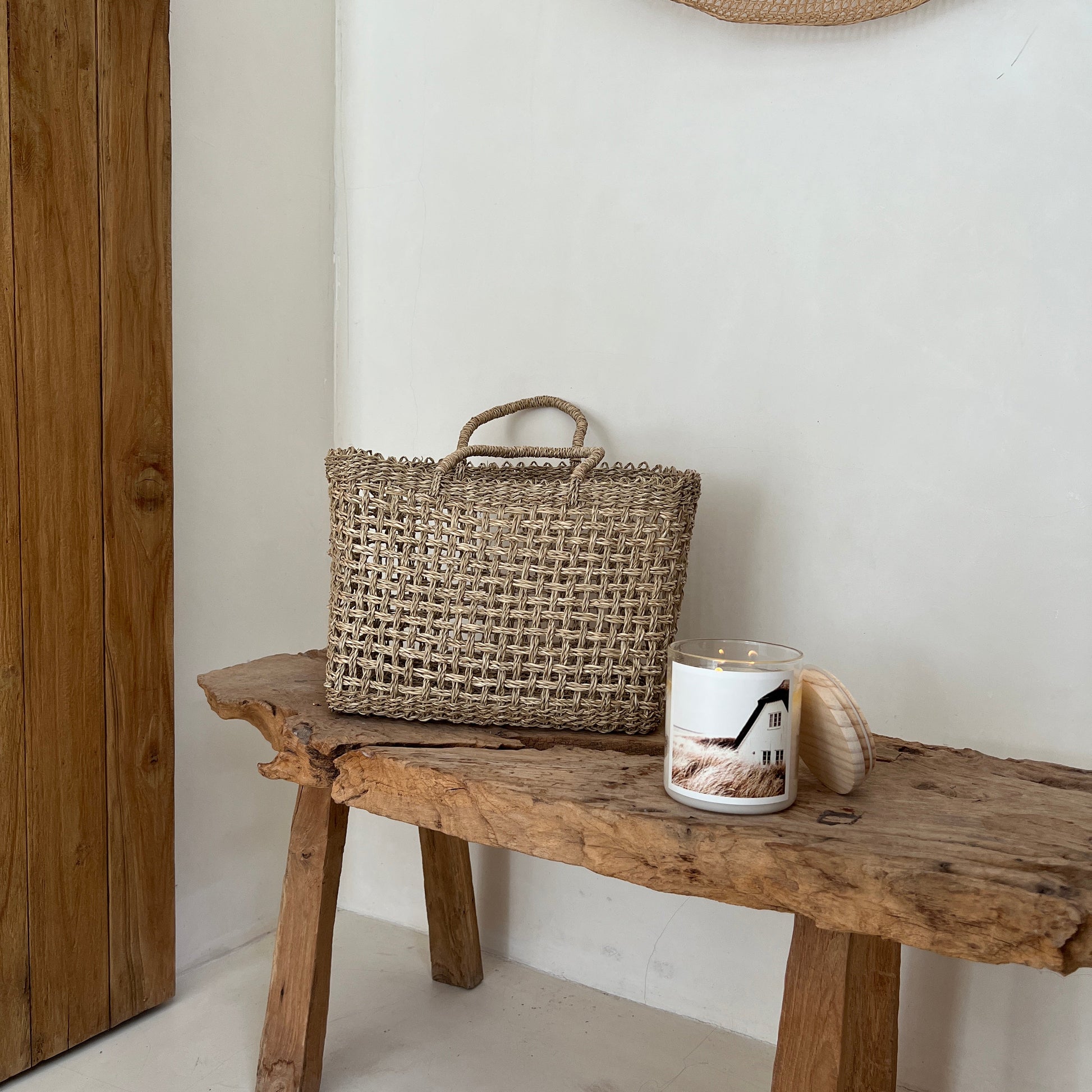Woven basket on a wooden stool against a white wall