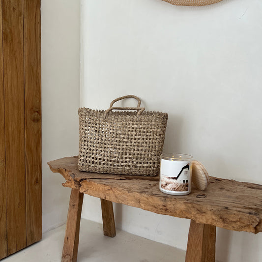 Woven basket on a wooden stool against a white wall