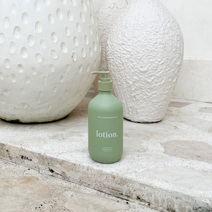 Matte green lotion in a decorative vase is placed on a textured stone floor, creating a serene and elegant atmosphere.