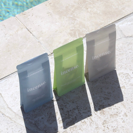 Three Incense bags in different colors hanging on a poolside ledge.