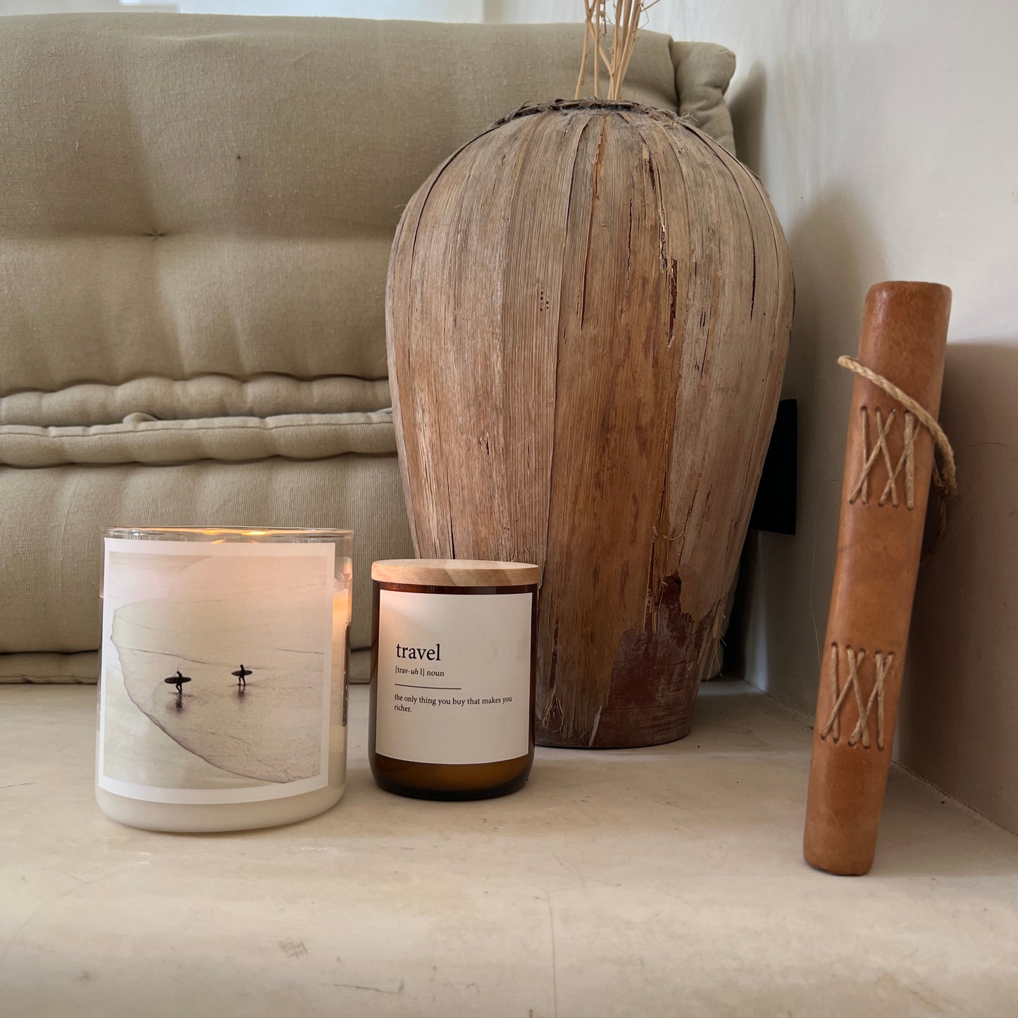 Decorative items including a wooden vase, candle, and book on a surface.