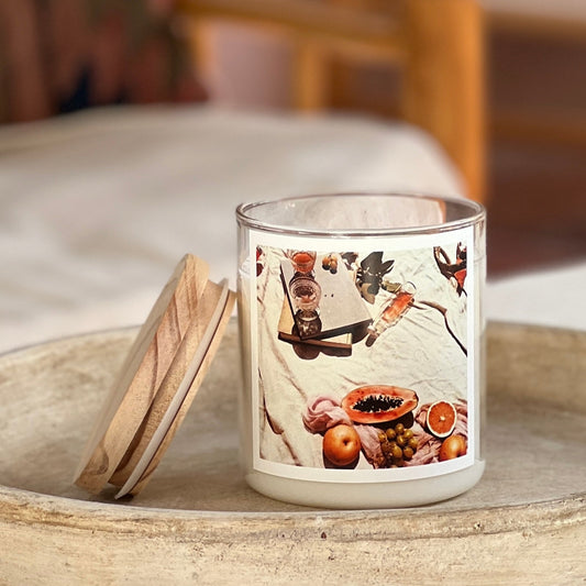 Candle with a decorative label featuring fruits on a wooden surface.