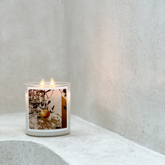 Candle with a decorative label on a white surface against a light gray wall