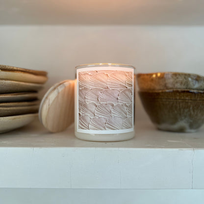 Ceramic candle holder with wick on a shelf with ceramic bowls and plates.
