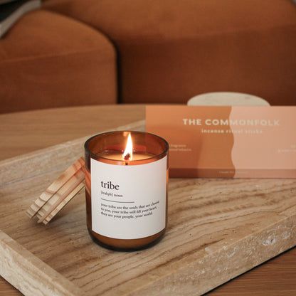 Candle labeled 'tribe' on a wooden tray with a blurred background