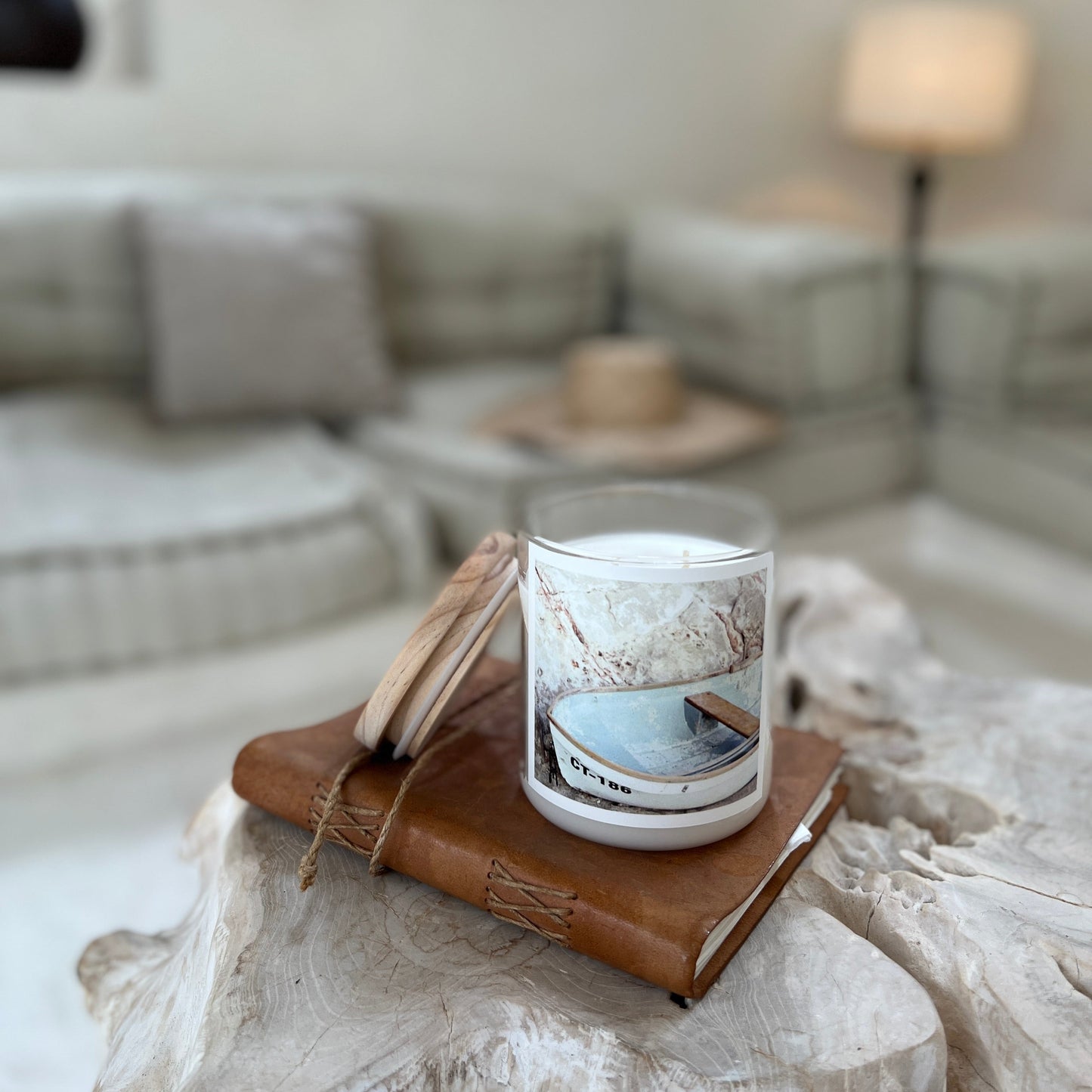 Candle with a scenic design on a wooden coaster in a living room setting