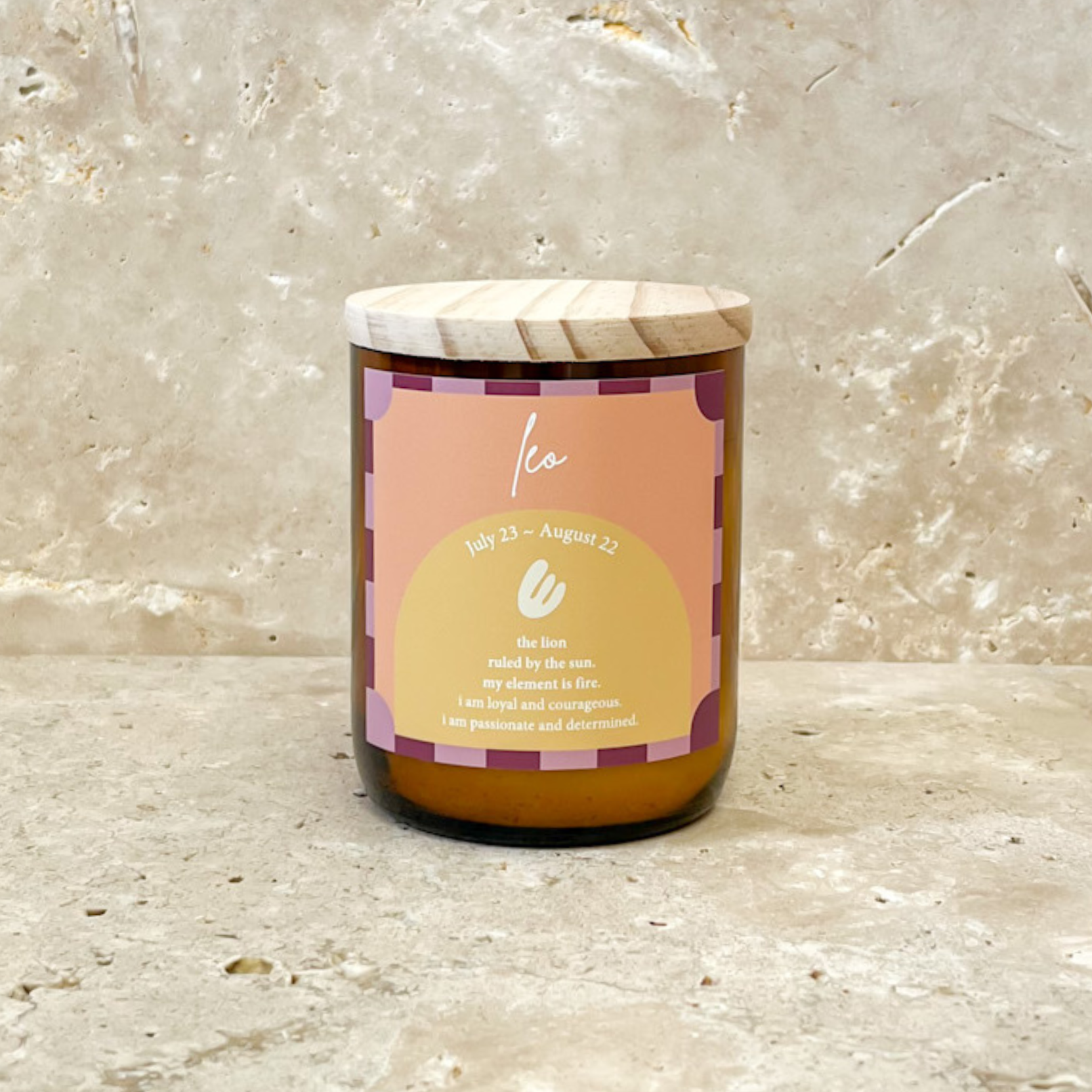 The Commonfolk scented candle with a wooden lid and a label featuring the Leo zodiac sign, set against a marble background.