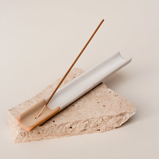 A beige ceramic incense holder from The Commonfolk with brown speckles on a beige background, designed to hold an incense stick.