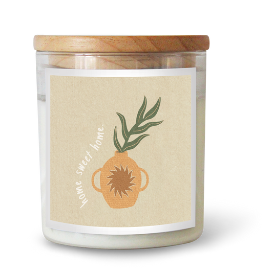 The Commonfolk scented candle has white wax, a beige label featuring a plant and the text 'home sweet home,' and a wooden lid.