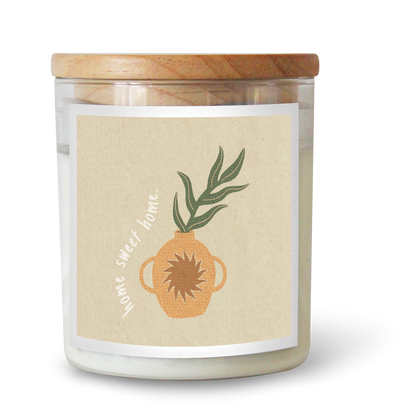 The Commonfolk scented candle has white wax, a beige label featuring a plant and the text 'home sweet home,' and a wooden lid.
