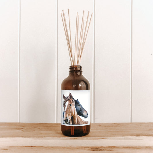 The Commonfolk room diffuser with a horse design label on a wooden surface and white paneled wall background.