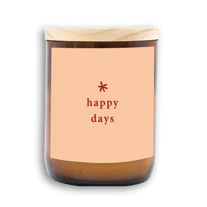 The Commonfolk scented candle has a wooden lid and a label that reads 'happy days' in red text. The candle wax is visible at the bottom.