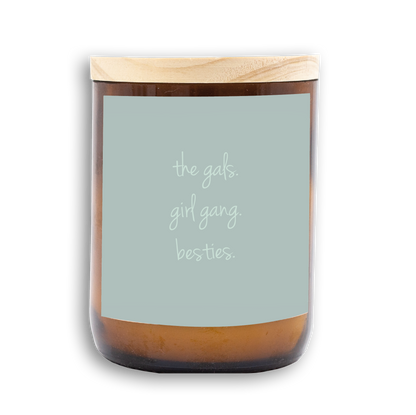 The Commonfolk scented candle with a wooden lid, white wax, and a label that reads 'the gals. girl gang. besties.'