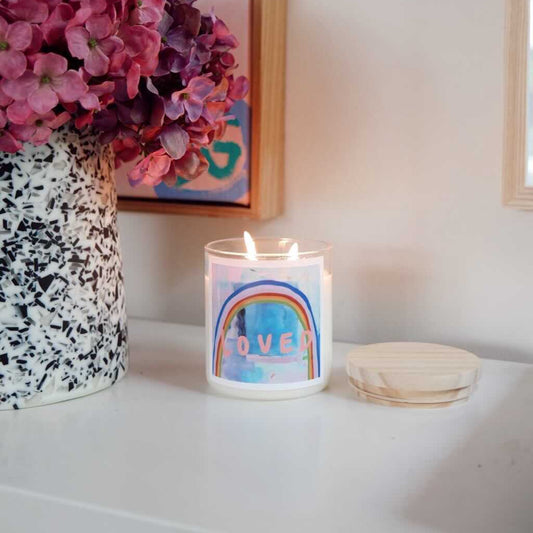 A candle on a white counter beside a colorful painting, creating a serene and artistic atmosphere.