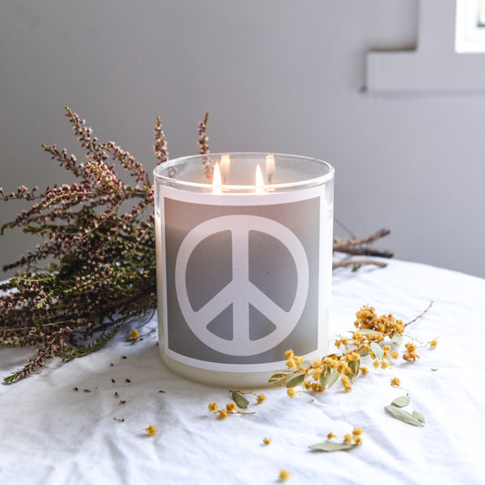 A candle featuring a peace sign rests on a table, symbolizing tranquility and harmony in the setting.