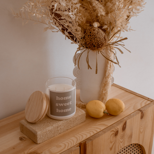A candle, a vase, and fresh lemons arranged on a rustic wooden table, creating a warm and inviting atmosphere.