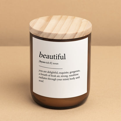 The Commonfolk scented candle with a wooden lid, a white label with the word 'beautiful' printed on it, and a definition in brackets.