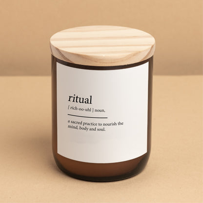 The Commonfolk scented candle with a wooden lid, amber jar, and a label that reads 'ritual' and 'a sacred practice to nourish the mind, body, and soul.'